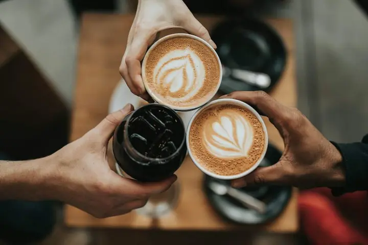 Two people holding lattes with latte art