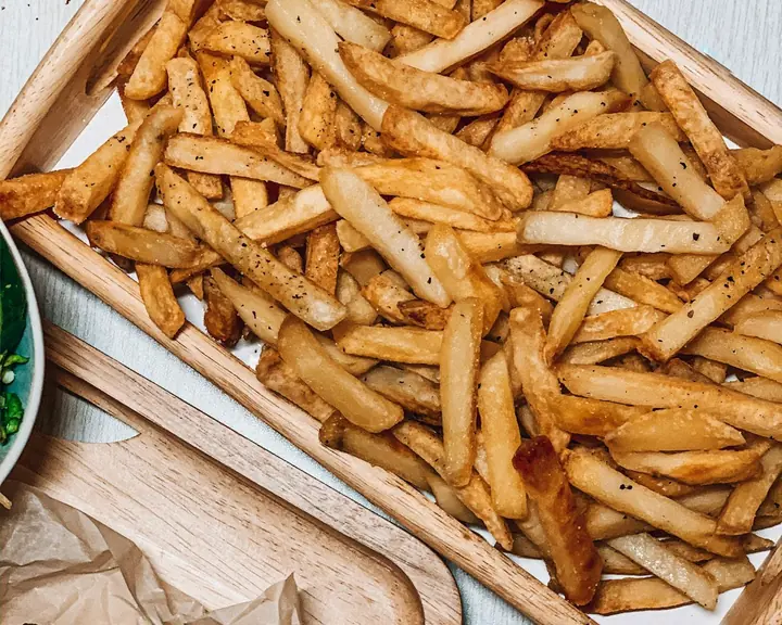 A tray of chips and chicken wings on a wooden board