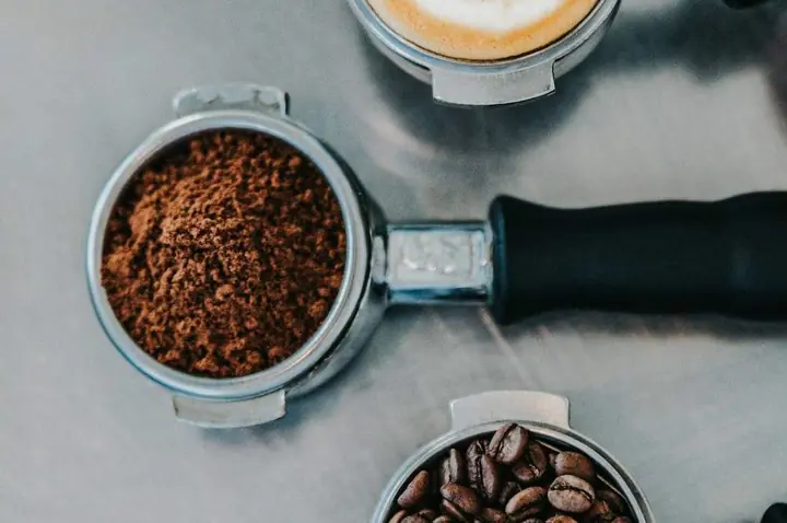 Latte art in a cup next to an espresso portafilter